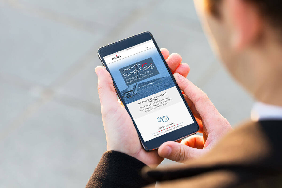 Man holding smartphone that is displaying Netrique website homepage